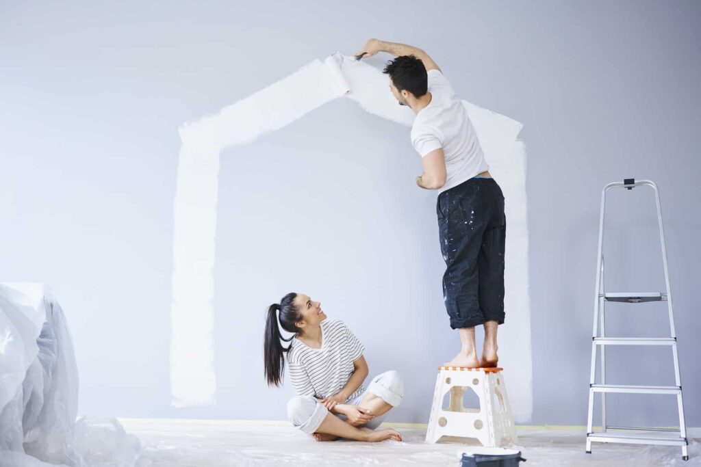 couple-painting-house-shape-on-wall-in-new-apartment.jpg